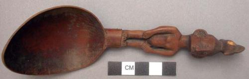 Wooden spoon, handle carved in human effigy: hands resting on flexed knees, chic