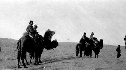 People riding camels across plain