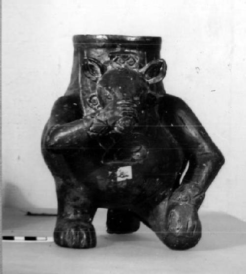 Ceramic effigy jar, zoomorph kneeling and holding snout, dark slip