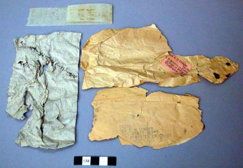 Paper fragments, one has illegible writing, one plain, two type-written