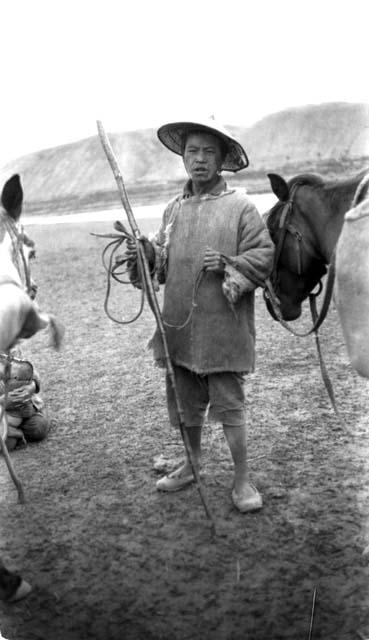 Man with horses standing by river