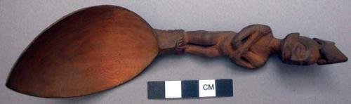 Wooden spoon, handle carved in human effigy: arms crossed on chest with hands re