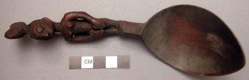 Wooden spoon, handle carved in human effigy: hands resting on flexed knees, hair