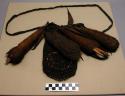 Tobacco net decorated with cocoons, pigtails, and furs. bamboo knives carried in
