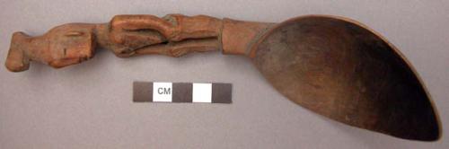 Wooden spoon, handle carved in human effigy: hands resting on flexed knees, carv