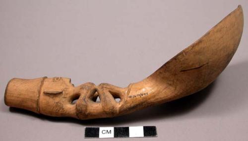 Wooden spoon, handle carved in human effigy: sitting position, elbows on knees,