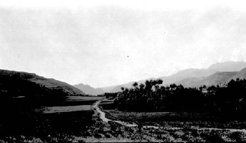 Road winding past fields, mountainous background