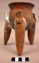 Pottery tripod jar - tops of legs end in animal effigies.  Reddish brown