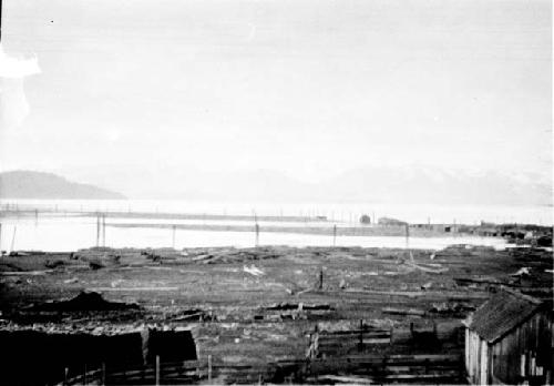 Scene with wooden structure on lake shore, distant mountains