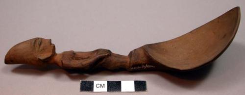 Wooden spoon, handle carved in human effigy: hands resting on flexed knees, coni