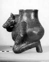 Ceramic effigy jar, zoomorph kneeling and holding snout, dark slip