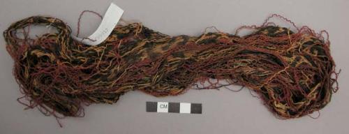 Organic, woven fiber, band fragment, red, yellow, brown, black, unravelled