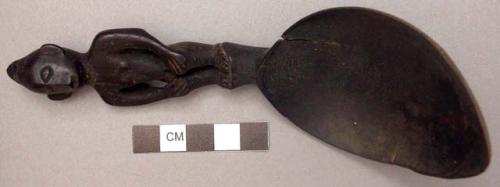 Wooden spoon, handle carved in human effigy: hands resting on flexed knees, no h