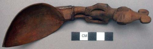 Wooden spoon, handle carved in human effigy: hands resting on flexed knees, hair