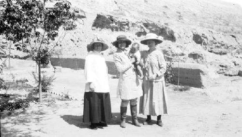 Three women with a baby in the desert