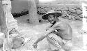 Man crouching near stone wall