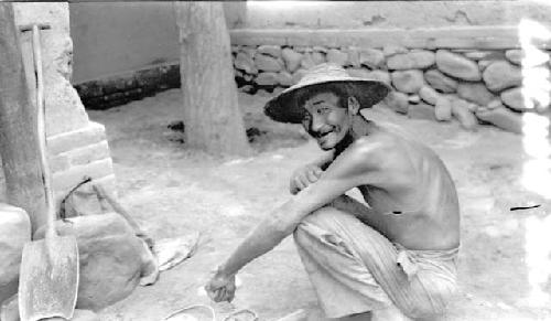 Man crouching near stone wall