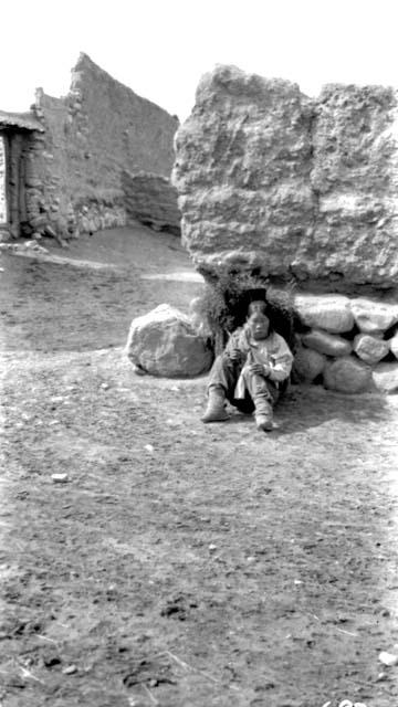 Person sitting against stone wall