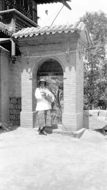 Woman with dog standing in archway attached to building