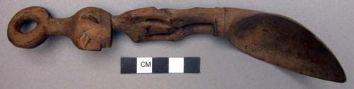Wooden spoon, handle carved in human effigy:female, hands resting on flexed knee