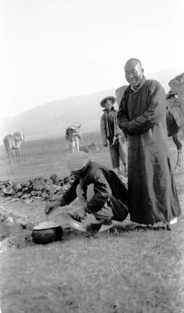 Person preparing food while others stand by with horses