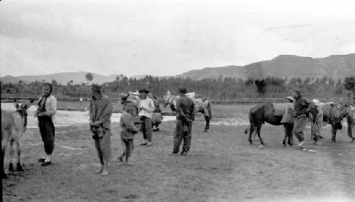 People with donkey and horses by river