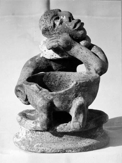 Pot 17, Grave 2. Pottery figure seated on low platform holding a small bowl