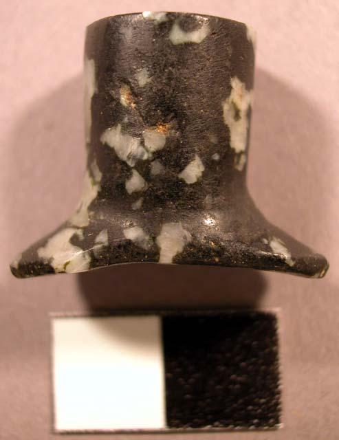 Flaked syenite labret. Head is oval, concave, and flared. Shaft is straight.