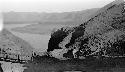 People and horses near bridge spanning river in mountains