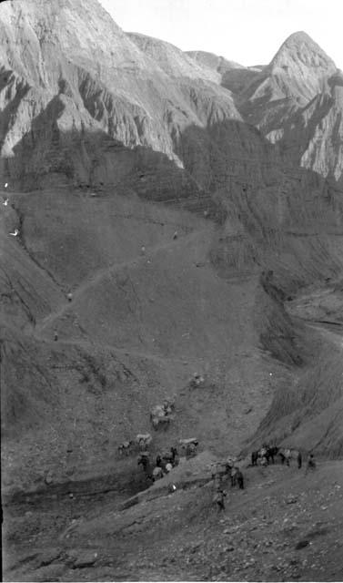 People with ponies carrying packs in mountains