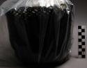 Plaited basket, cylindrical shape, coated with black waxy substance. Extensive d