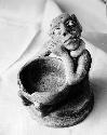 Pot 17, Grave 2. Pottery figure seated on low platform holding a small bowl