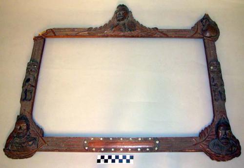 Frame, carved, 3 human portraits and 2 tiki figures, linear design, paua shell i