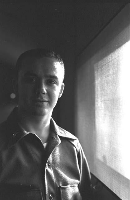 Man standing next to screened window.