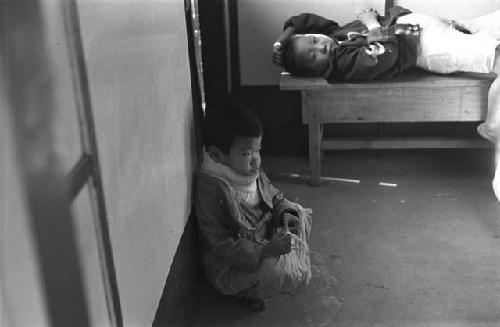 Child laying on bench; one crouching on floor.