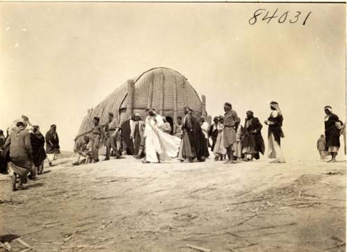 Life scene with group of men and house in the background