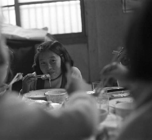 Children at table eating food with chopsticks