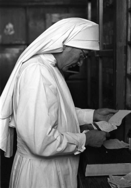 Nun with glasses and paper and pen.