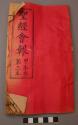 Book, partial red cover with black Chinese character print; worn