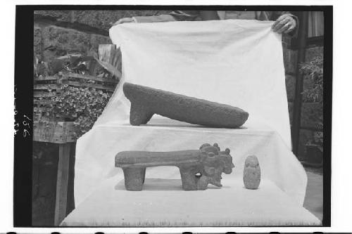 Two metates and small stone sculptures.