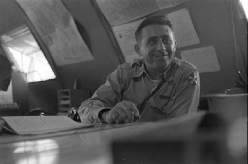 Military man (Cohen name tag) sitting at desk with book.