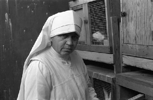 Nun in front of Guinea Pig cages.