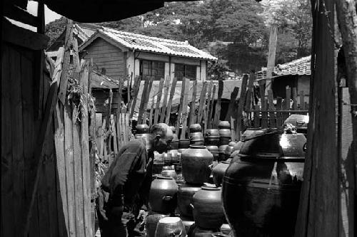 Man in junkyard with piles of pots.