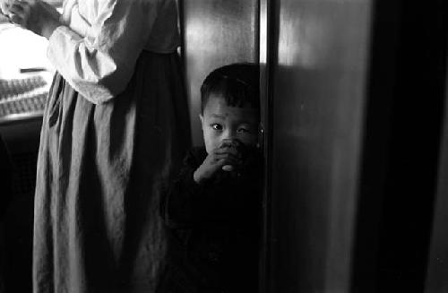 Boy with hand to face, woman next to him.