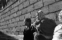 Two women standing in front of a cinder block wall.