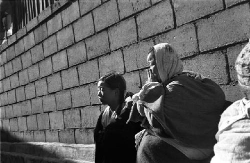 Two women standing in front of a cinder block wall.