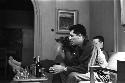 Two military men sitting on couch with liquor bottles on table.