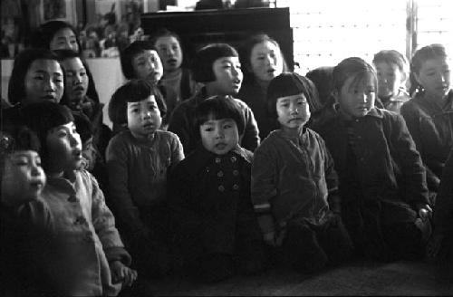 Group of sixteen young children singing (inside)