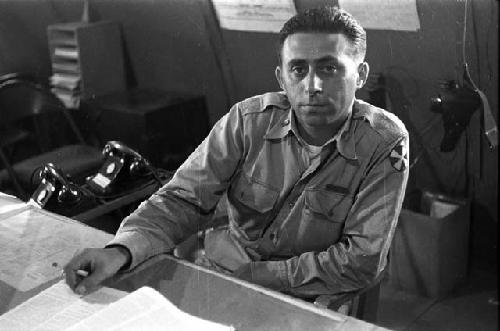 Military man (Cohen name tag) sitting at desk with book.