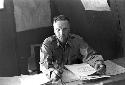 Military Man (Johnson name tag) sitting at desk with papers.